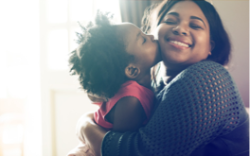 A girl kissing her mom on her cheek